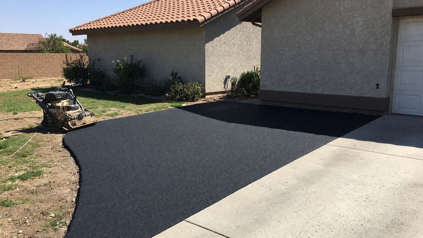 Freshly paved two-car asphalt driveway at a stucco home — asphalt paving in Riverside, CA