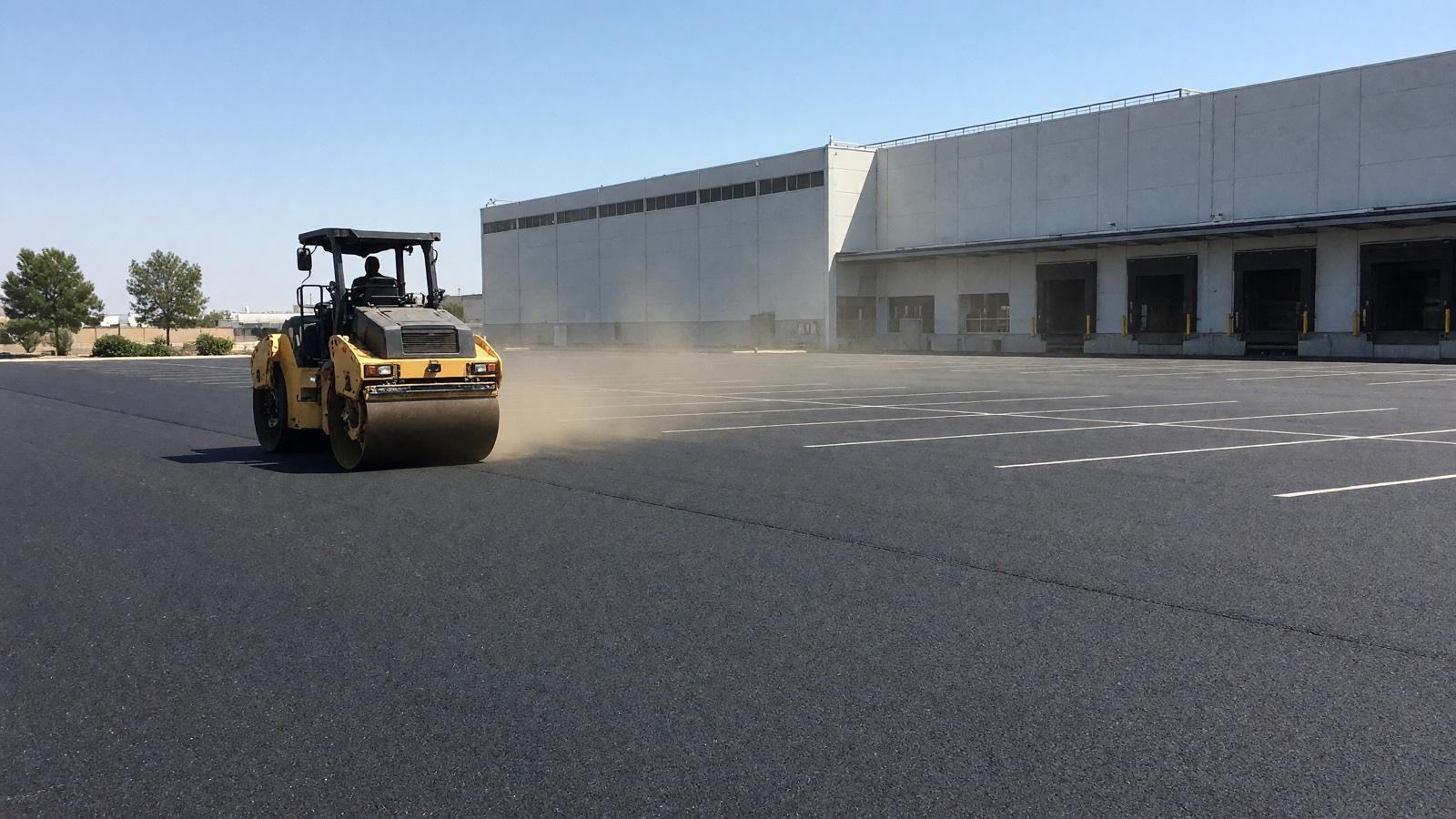 New asphalt parking lot beside a tilt-up warehouse — asphalt paving in Riverside, CA