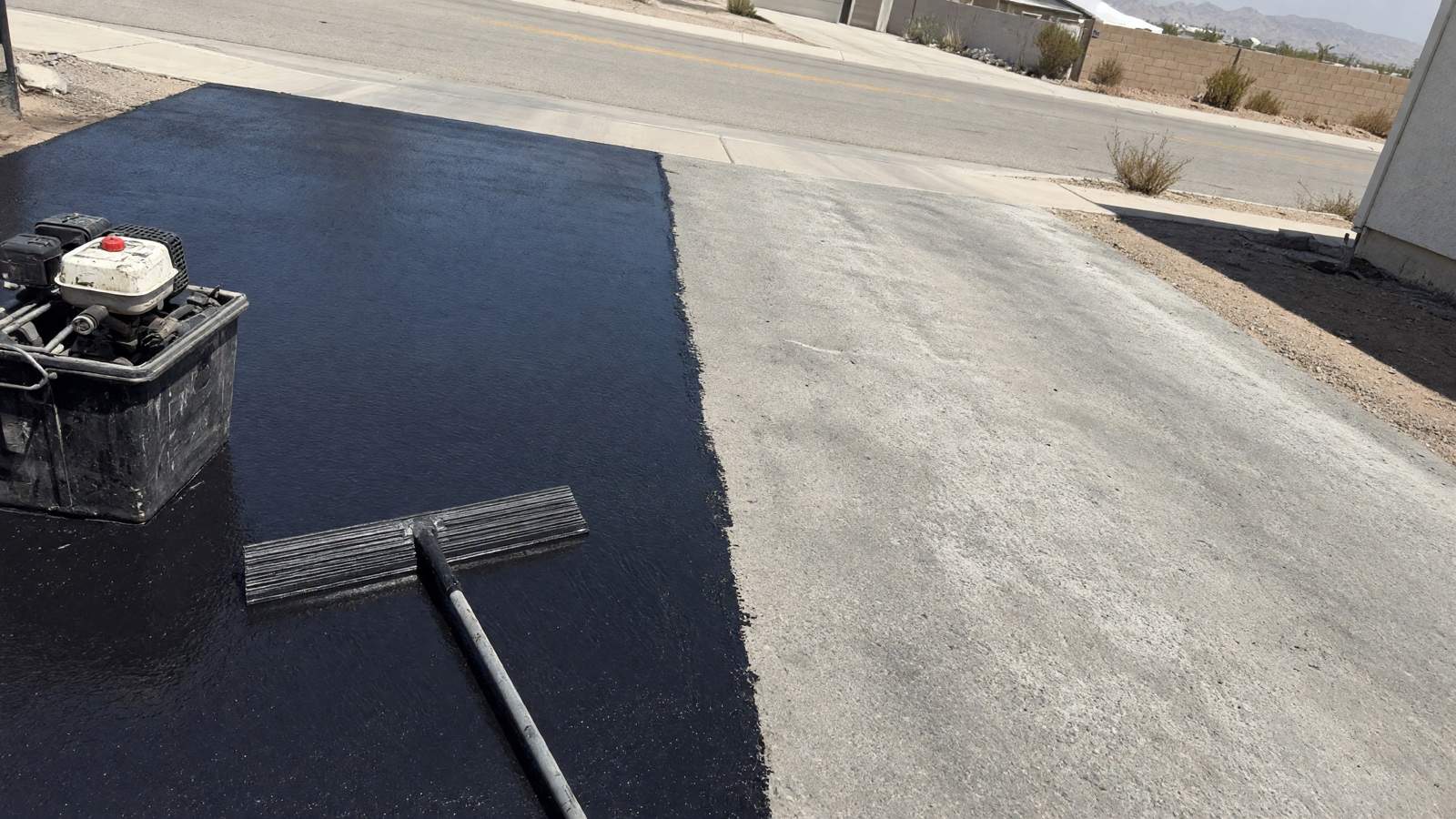 Sealcoat being squeegeed onto a faded asphalt driveway — asphalt paving in Riverside, CA